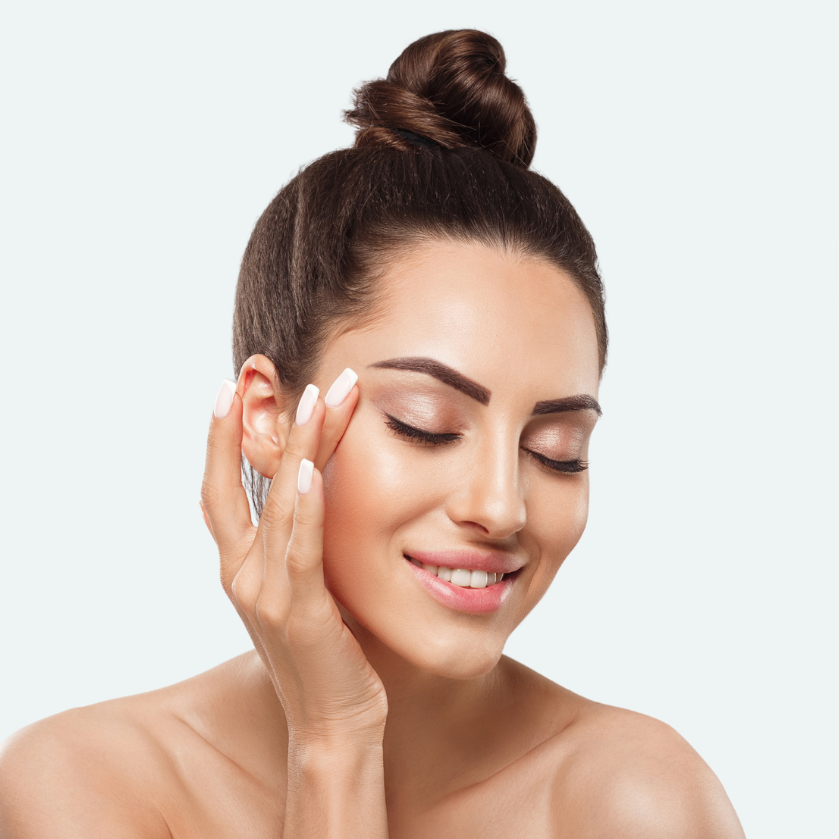 Woman with a bun hairstyle touching her face against after using a micrcurrent device with AbSonic gel