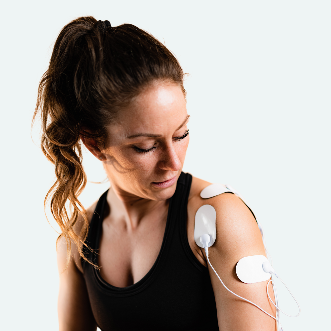 EMS electrode pads placed on shoulder for at-home muscle stimulation and recovery
